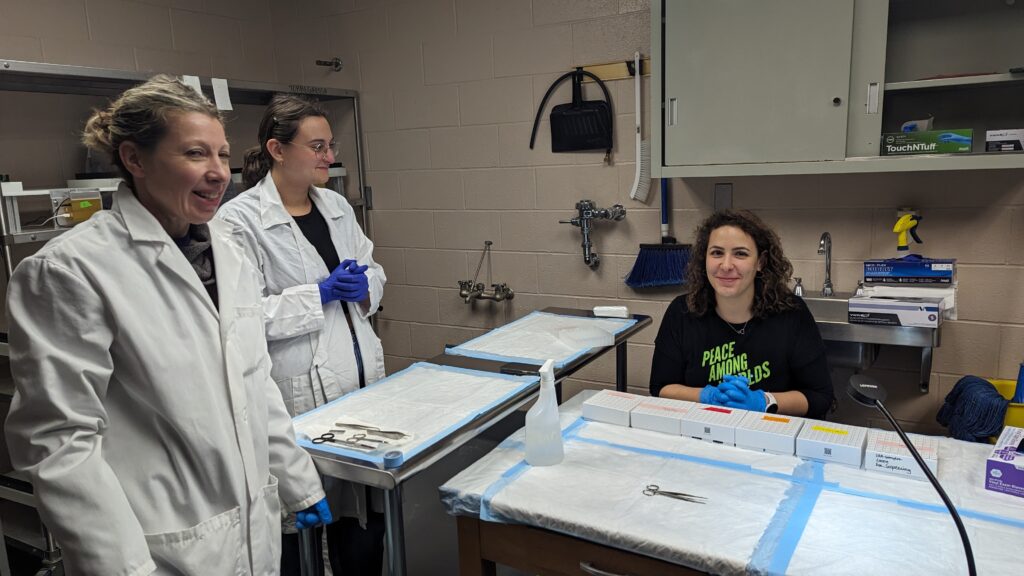 Three lab members working with equipment at the bench
